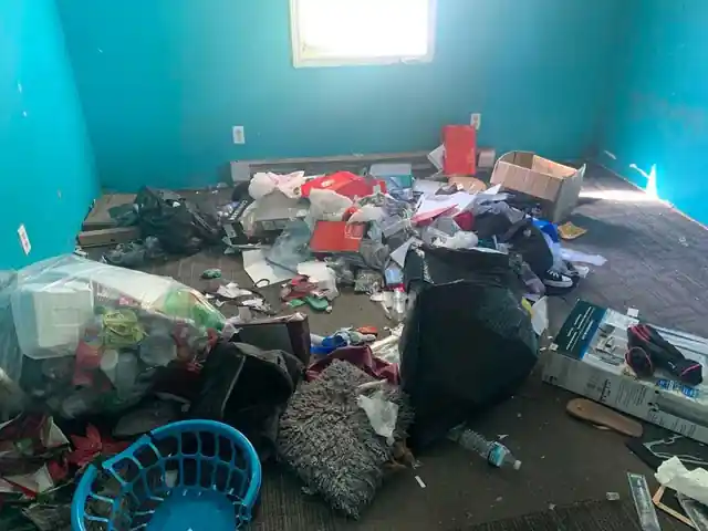 Teal-walled bedroom buried in clothes, bags and a laundry basket