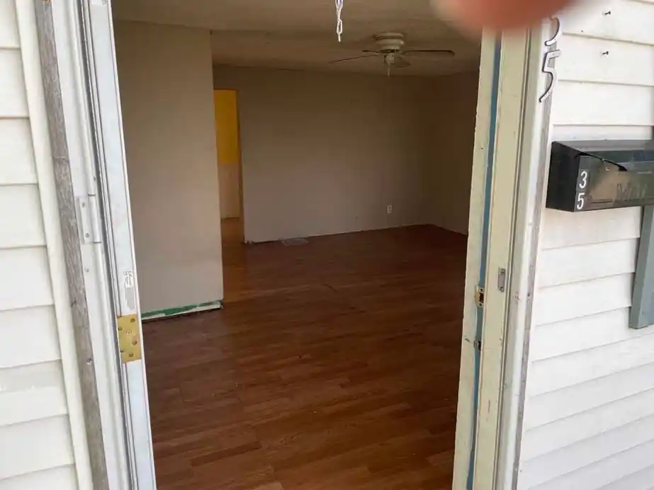 Empty room with wood-look floor seen through an open doorway