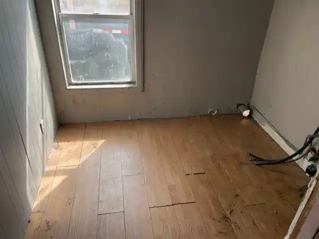 Small room with honey plank floor, grey walls and one window