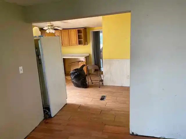 Kitchen seen through a doorway with a yellow wall, white wainscot and a white refrigerator