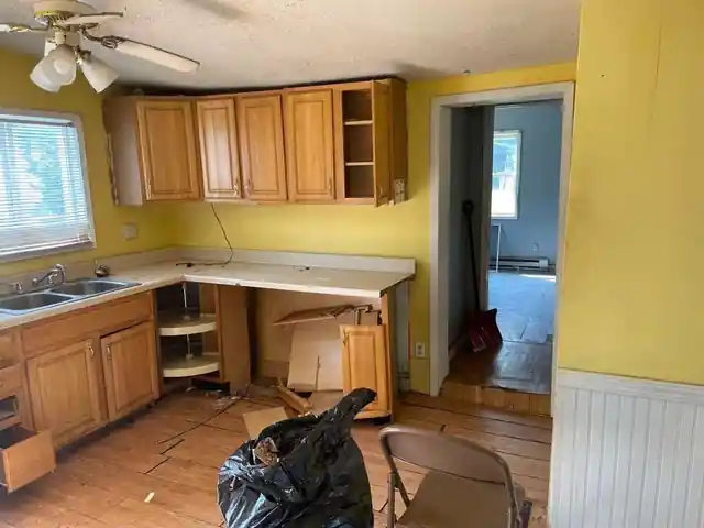 Kitchen with oak cabinets, yellow walls and a bare plank floor