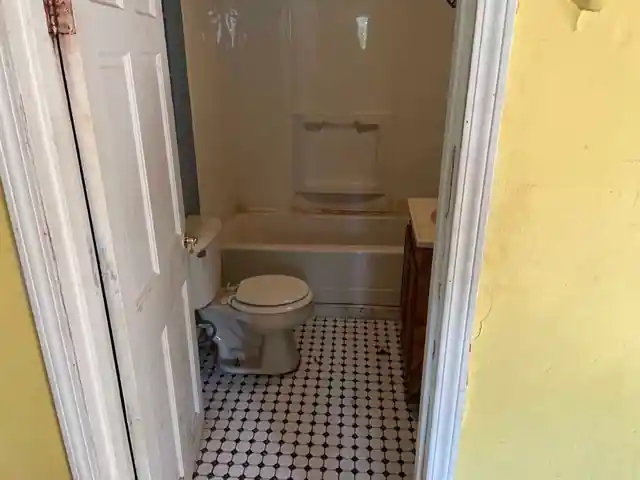 Bathroom with a white tub, toilet and black and white checker tile floor