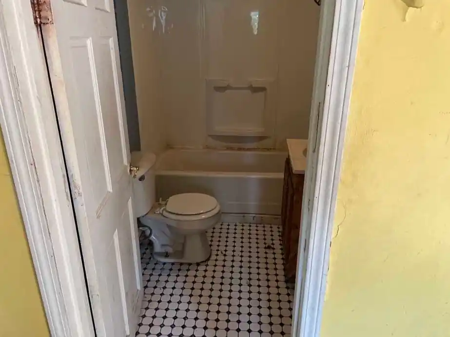 Bathroom with a white tub, toilet and black and white checker tile floor