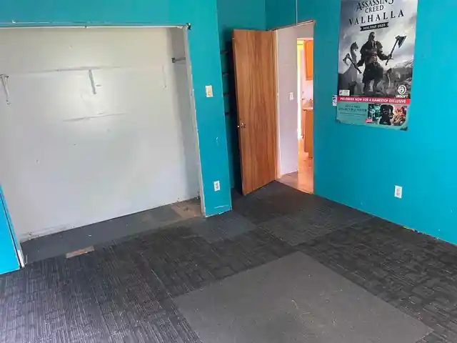 Bedroom with teal walls, grey carpet tile and an empty closet