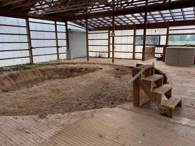 Ring of bare sand where the pool stood, wood deck boards around it and a small set of wooden steps