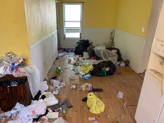 Yellow-walled room with white wainscot, floor covered in bags and trash