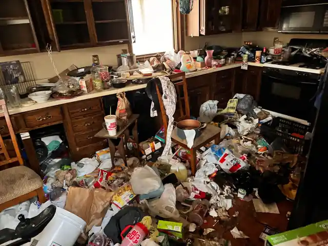 Kitchen with oak cabinets and a floor covered in takeout cups, food boxes and trash bags